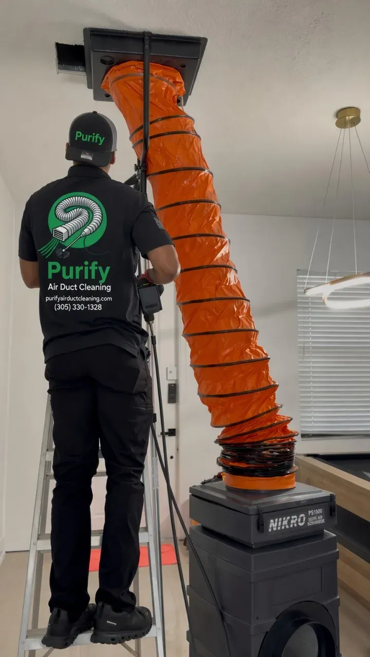 Purify technician connecting a negative-air duct at a ceiling opening